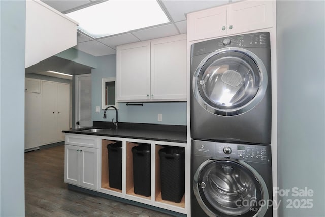 laundry room with cabinets, stacked washer and dryer, dark hardwood / wood-style floors, and sink