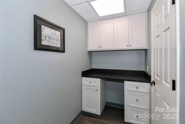 unfurnished office featuring a paneled ceiling and dark hardwood / wood-style floors