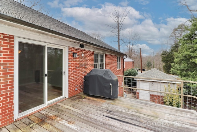 wooden terrace featuring an outbuilding, a grill, and a garage