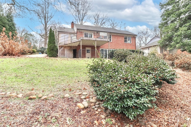 back of house featuring a balcony and a yard