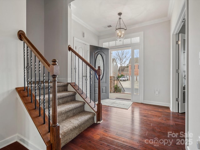 foyer with hardwood / wood-style floors, baseboards, visible vents, and ornamental molding