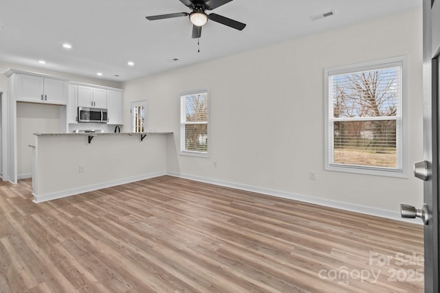 unfurnished living room with ceiling fan and light hardwood / wood-style flooring