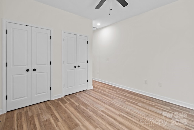 unfurnished bedroom with two closets, ceiling fan, and light hardwood / wood-style flooring