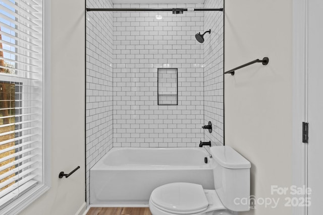 bathroom featuring hardwood / wood-style flooring, toilet, and tiled shower / bath combo