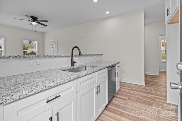 kitchen with light stone counters, stainless steel dishwasher, sink, and white cabinets