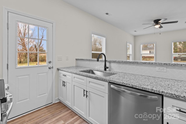 kitchen with white cabinetry, stainless steel dishwasher, sink, and light stone counters