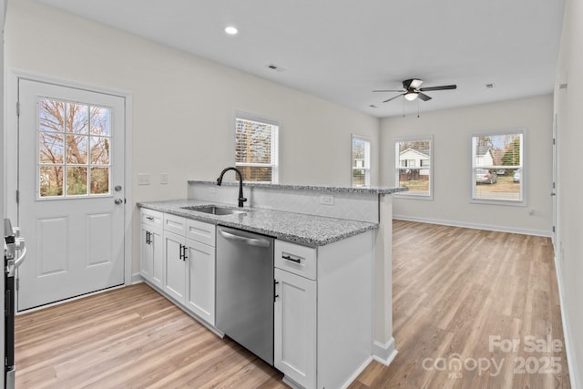 kitchen with sink, white cabinetry, stainless steel dishwasher, kitchen peninsula, and light stone countertops