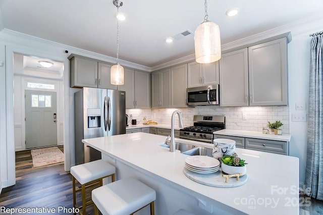 kitchen featuring gray cabinets, appliances with stainless steel finishes, hanging light fixtures, dark hardwood / wood-style floors, and decorative backsplash