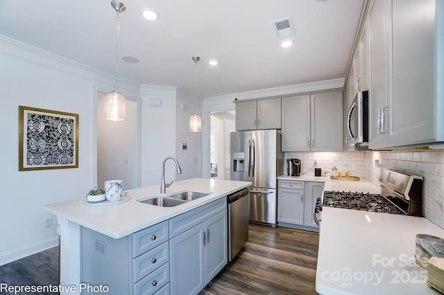 kitchen featuring sink, tasteful backsplash, decorative light fixtures, appliances with stainless steel finishes, and an island with sink