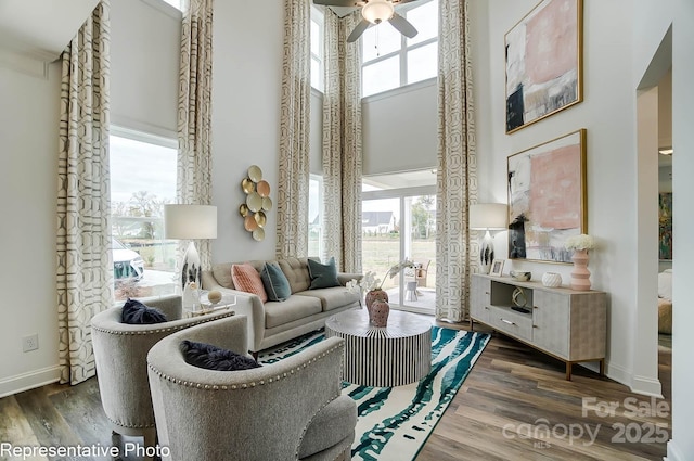 sitting room with ceiling fan, dark hardwood / wood-style floors, a healthy amount of sunlight, and a high ceiling