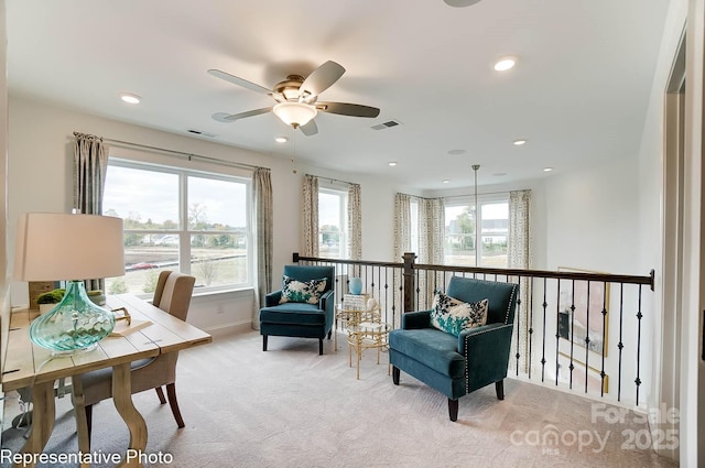 living area featuring plenty of natural light, light carpet, and ceiling fan