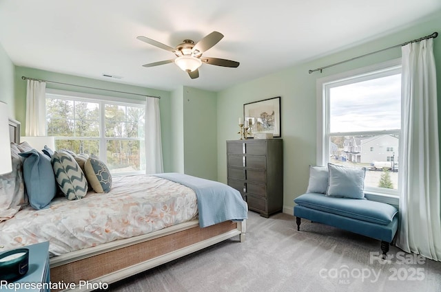 bedroom with multiple windows, light colored carpet, and ceiling fan