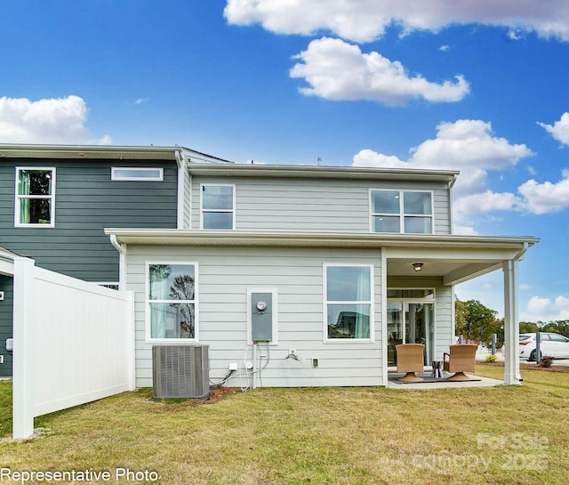 rear view of house with cooling unit, a patio, and a lawn