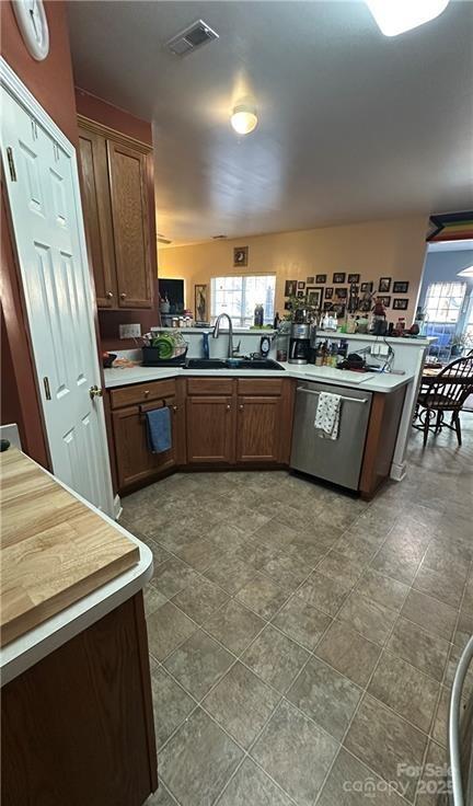 kitchen with a wealth of natural light, sink, stainless steel dishwasher, and kitchen peninsula