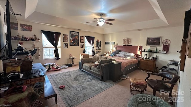 carpeted bedroom featuring a raised ceiling and ceiling fan