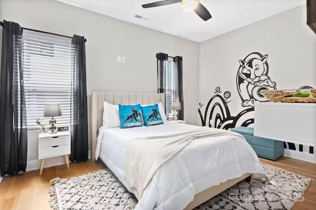 bedroom featuring ceiling fan, multiple windows, and light wood-type flooring