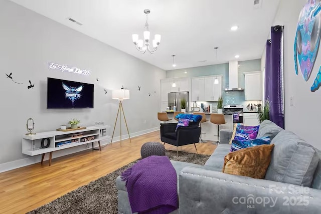 living room with an inviting chandelier and light hardwood / wood-style flooring