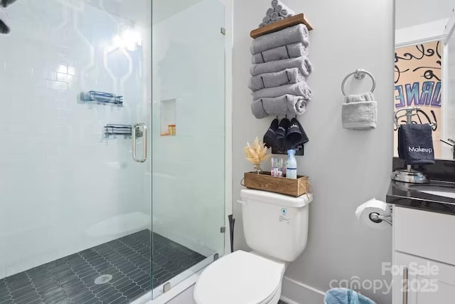 bathroom featuring vanity, a shower with door, and toilet