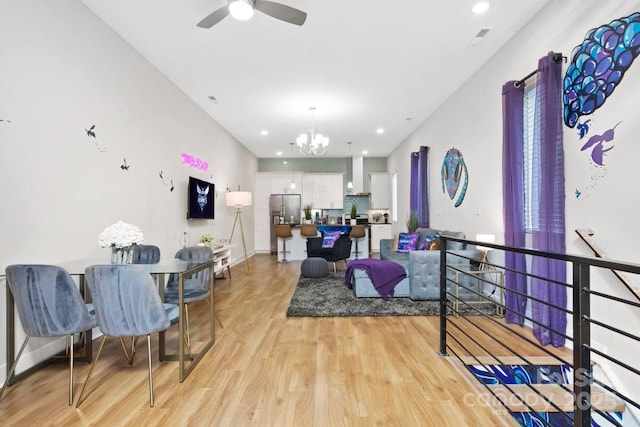 living room with ceiling fan with notable chandelier and light hardwood / wood-style flooring