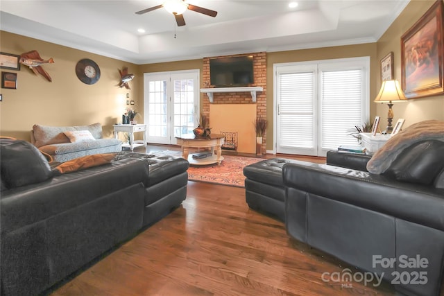 living room featuring ornamental molding, dark wood-type flooring, ceiling fan, and a tray ceiling