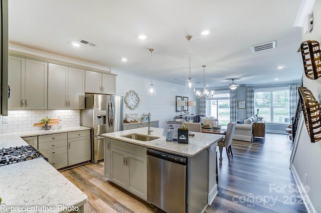 kitchen featuring sink, decorative light fixtures, gray cabinets, an island with sink, and stainless steel appliances