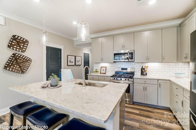 kitchen with a kitchen island with sink, sink, crown molding, and stainless steel appliances