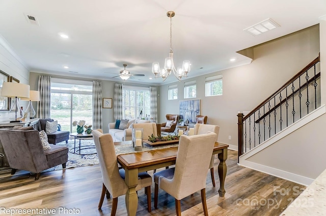 dining space featuring hardwood / wood-style flooring, ornamental molding, and ceiling fan with notable chandelier