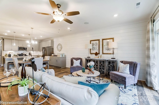 living room with ceiling fan with notable chandelier and dark hardwood / wood-style flooring