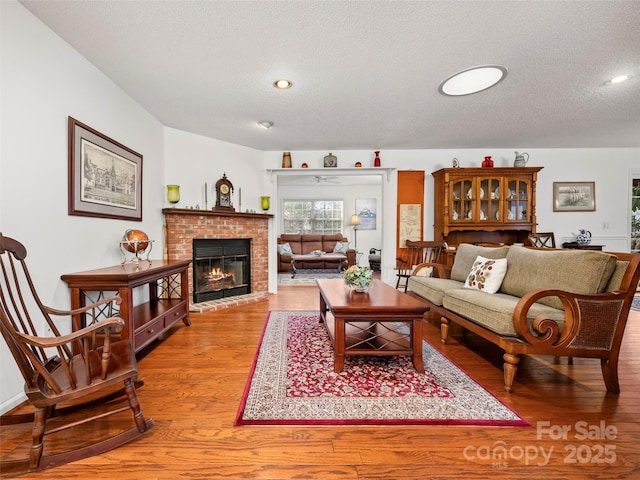 living room with hardwood / wood-style flooring, a textured ceiling, and a fireplace