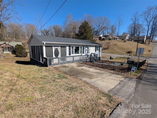 view of front of property featuring a sunroom, fence, and a front lawn