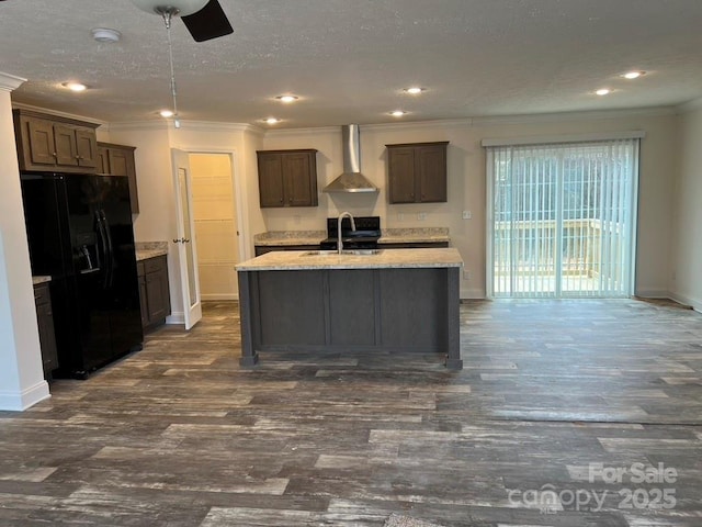 kitchen with ornamental molding, a sink, wall chimney range hood, a textured ceiling, and black fridge