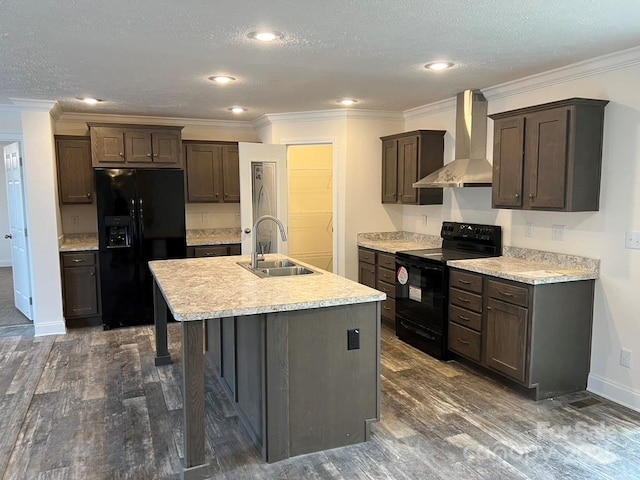 kitchen featuring a kitchen island with sink, a sink, light countertops, wall chimney range hood, and black appliances