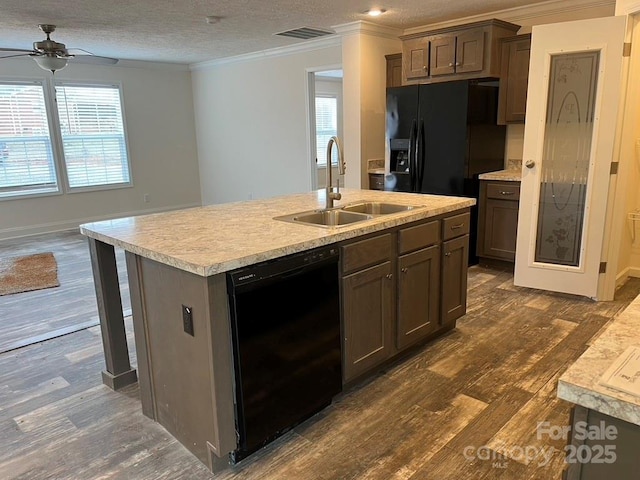 kitchen featuring dark wood-style floors, a kitchen island with sink, light countertops, black appliances, and a sink