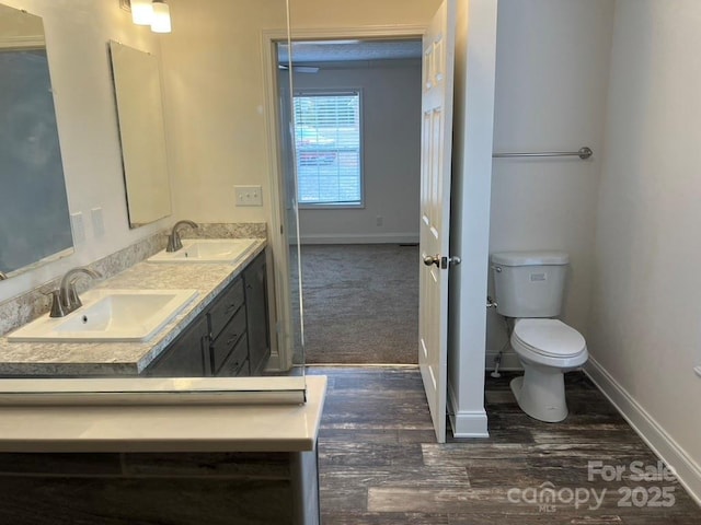 bathroom featuring double vanity, baseboards, toilet, and a sink