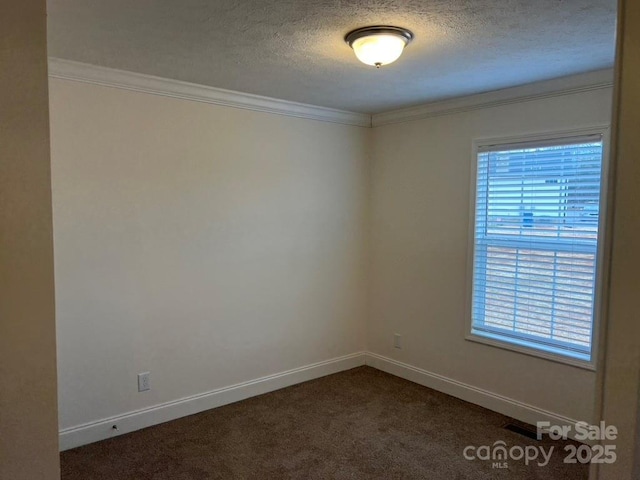 spare room featuring a textured ceiling, dark colored carpet, ornamental molding, and baseboards