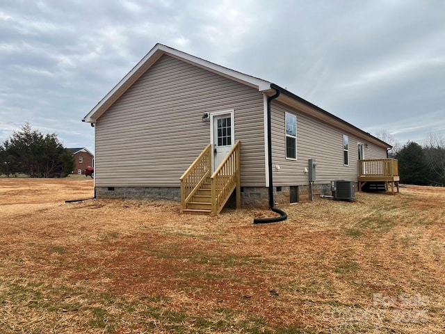 view of side of property featuring entry steps, crawl space, a yard, and central AC unit