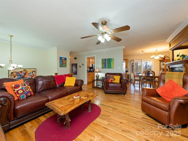 living area with ceiling fan with notable chandelier, light wood-type flooring, crown molding, and a textured ceiling