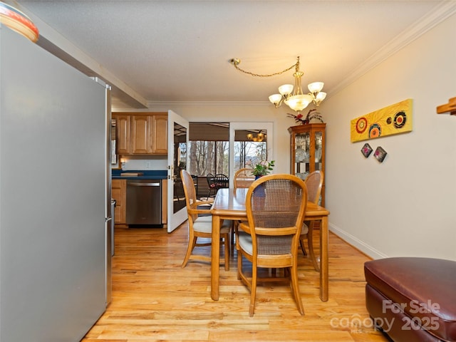 dining space with light wood-style flooring, crown molding, baseboards, and a chandelier