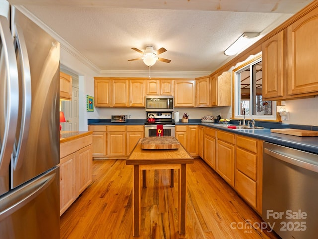 kitchen with light brown cabinetry, crown molding, a sink, and stainless steel appliances