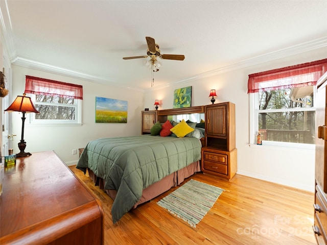 bedroom with multiple windows, ornamental molding, baseboards, and light wood-style floors