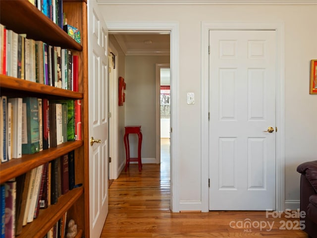 hallway featuring baseboards, wood finished floors, and crown molding