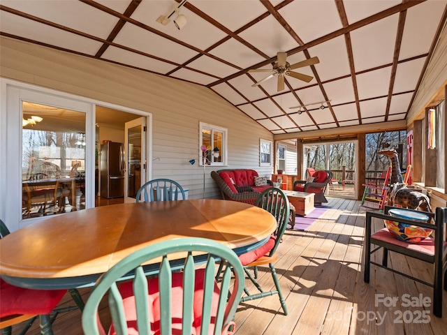 sunroom / solarium with wood finished floors, vaulted ceiling, a deck, and wood walls