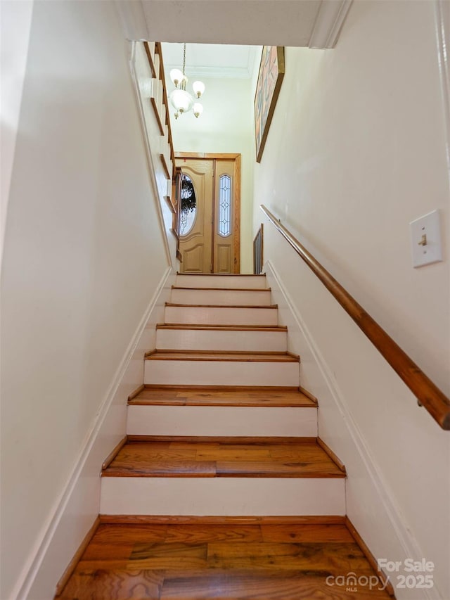 staircase with an inviting chandelier and wood finished floors