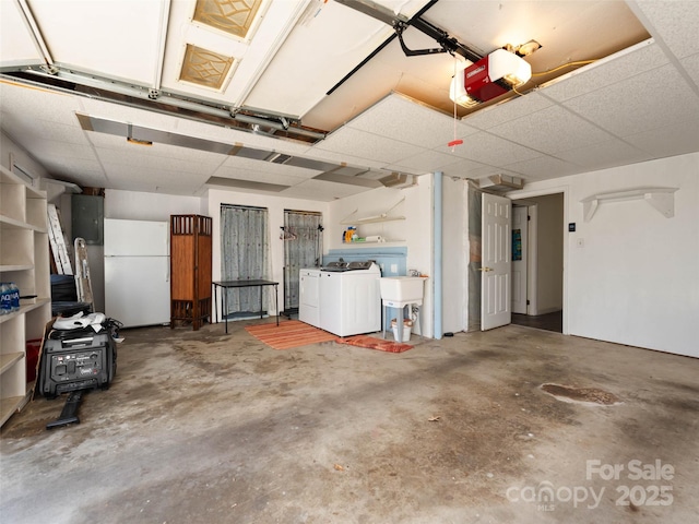 garage with washing machine and clothes dryer, a garage door opener, and freestanding refrigerator
