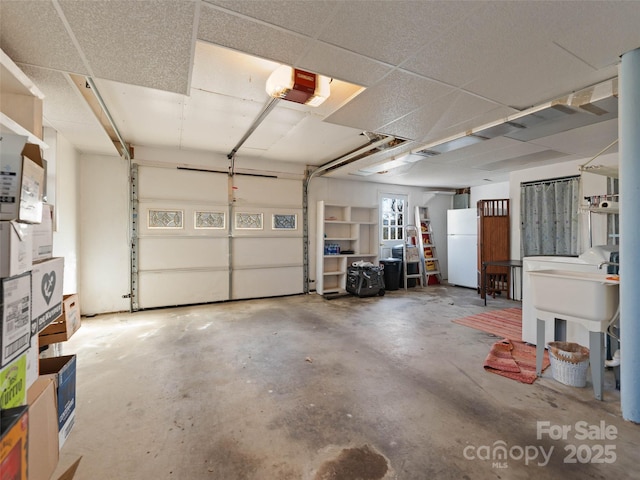 garage featuring a garage door opener, a sink, and freestanding refrigerator