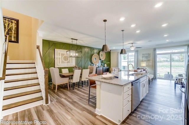 kitchen featuring pendant lighting, sink, white cabinetry, a kitchen island with sink, and stainless steel dishwasher