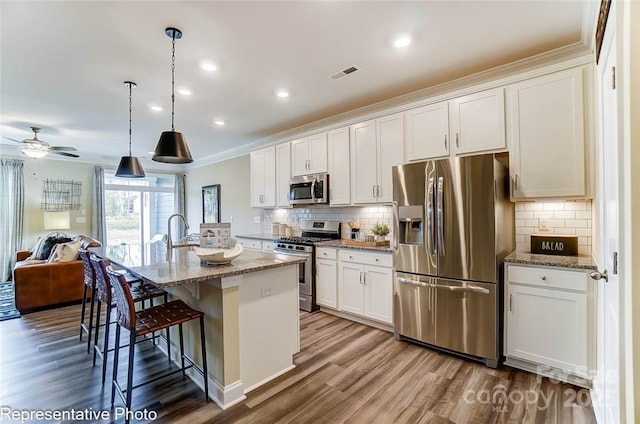 kitchen with appliances with stainless steel finishes, a kitchen island with sink, and white cabinets