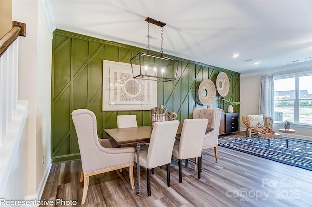 dining room with hardwood / wood-style floors, crown molding, and a notable chandelier