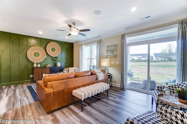 living room featuring hardwood / wood-style floors, crown molding, and ceiling fan