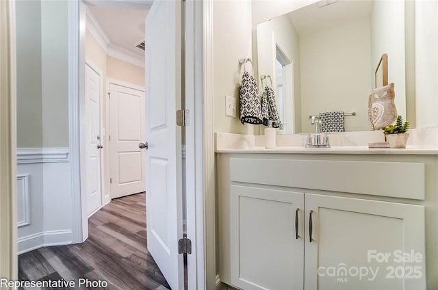 bathroom featuring vanity, wood-type flooring, and ornamental molding